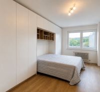 Schlafzimmer in einer 3-Zimmer-Wohnung mit Bett, Einbauschränken und Boden in Holzoptik.