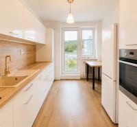 Eine Küche in einer 3-Zimmer-Wohnung mit einem Boden in Holzoptik, einer weißen Küchenzeile und einem Ofen.