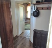 Ein schmaler Flur in einer 2-Zimmer-Wohnung mit einem Holzboden und einem Schrank.
