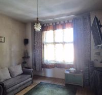 Wohnzimmer in einer 2-Zimmer-Wohnung mit Sofa, Fernseher und Holzboden.