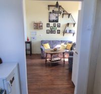 Innenraum einer 2-Zimmer-Wohnung mit Holzboden und bequemen Sitzgelegenheiten.