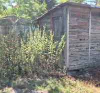 Ein Holzunterstand, umgeben von Vegetation, im Hof an der Straße Za 3 mostami in Nové Zámky.