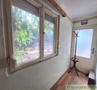 Ein enger Flur in einem Einfamilienhaus mit einem Fenster, einem Kleiderhaken und einem Boden mit Holzdekor.