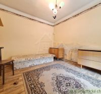 Ein Zimmer mit einem Bett, einem Stuhl und Teppichen, einem Boden mit Holzdekor, Eckmöbel.
