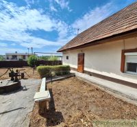Ein Einfamilienhaus in Kamenica nad Hronom mit Hof, Brunnen und Bank auf einem sonnigen Grundstück.