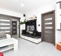 Wohnzimmer in einer 3-Zimmer-Wohnung mit Holzboden und weißen Möbeln.