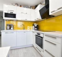Küche in einer 3-Zimmer-Wohnung mit weißer Küchenzeile und gelben Fliesen.