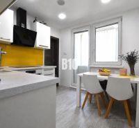 Küche in einer 3-Zimmer-Wohnung mit weißen Möbeln und gelben Fliesen bei dem Herd.