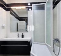 Ein Badezimmer in einer 3-Zimmer-Wohnung mit einer Badewanne, einem Waschbecken und einem Boden in Holzoptik.