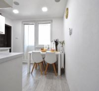 Essbereich mit Tisch und Stühlen auf einem Boden mit Holzdekor in einer 3-Zimmer-Wohnung.