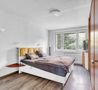 Schlafzimmer mit Bett und Holzboden in einer Zweizimmerwohnung.