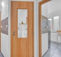 Innenraum einer 2-Zimmer-Wohnung mit Holztüren und verglastem Eingang zur Küche.