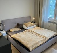Schlafzimmer mit großem Bett, Nachttischen und Boden mit Holzdekor in einer 3-Zimmer-Wohnung.