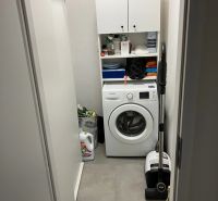 Waschküche mit Waschmaschine und Aufbewahrungsschränken in einer 3-Zimmer-Wohnung.