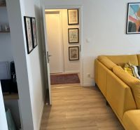 Heller Boden mit Holzdekor und gelbes Sofa in einer 3-Zimmer-Wohnung.