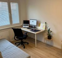 Ein Arbeitsbereich in einer 3-Zimmer-Wohnung mit Holzboden und ausziehbarem Sofa.