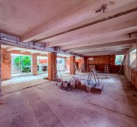 Unvollendete Geschäftsräume mit Betonboden, Leitern und Baumaterial.