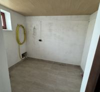 Waschküche mit gefliestem Boden und Decke mit Holzdekor in einem Einfamilienhaus.