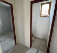 Im Einfamilienhaus befinden sich zwei Räume mit Betonboden und kleinem Fenster.