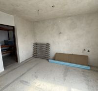 Innenraum eines Einfamilienhauses mit unvollendeten Wänden und Boden, mit Materialien auf dem Boden.