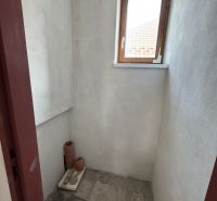 Ein kleiner Raum mit einem Fenster in einem Einfamilienhaus, unverputzte Wände, Fliesenboden.