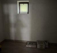 Dachzimmer in einem Einfamilienhaus mit Kisten und kleinem Fenster.
