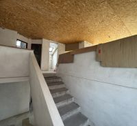 Innenraum eines Einfamilienhauses mit Treppe, weißen Wänden und OSB-Platten an der Decke.