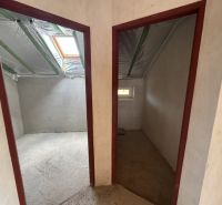 Dachbodenräume eines Einfamilienhauses mit doppeltem Eingang, Dachfenster und unvollendeten Wänden.