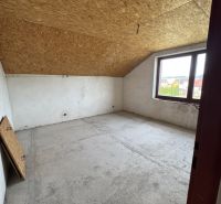 Ein Dachzimmer in einem Einfamilienhaus mit Holzbalkendecke und großem Fenster.