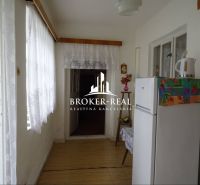 Innenraum eines Einfamilienhauses mit einem weißen Kühlschrank und einem dekorierten Boden in Holzoptik.