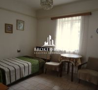 Ein Zimmer in einem Einfamilienhaus mit Bett, Sesseln und Tisch, dekorative Bilder an der Wand.