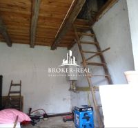 Innenraum eines Einfamilienhauses mit Holzdecke und Leiter, eingerichtet mit Werkzeugen und Kisten.