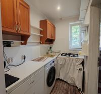 Küche in einer 3-Zimmer-Wohnung mit Holzboden, Waschmaschine und Oberschränken.