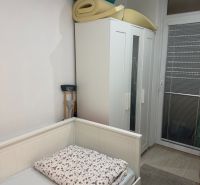 Ein Zimmer mit Bett, Kleiderschrank und zusammengerollten Matratzen in einer 2-Zimmer-Wohnung.