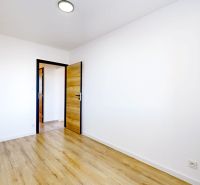Ein Zimmer in einer 3-Zimmer-Wohnung mit einem Boden in Holzoptik und weißen Wänden.