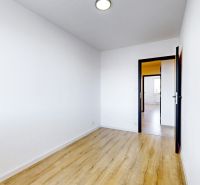 Ein geräumiges Zimmer in einer 3-Zimmer-Wohnung mit einem Holzboden und weißen Wänden.