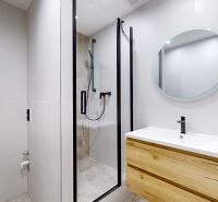 Badezimmer mit Duschkabine und Möbeln mit Holzdekor in einer 3-Zimmer-Wohnung.