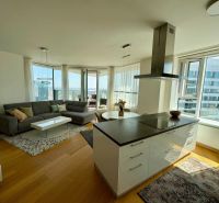 Helles Wohnzimmer mit Holzboden in einer 3-Zimmer-Wohnung, mit Blick aus großen Fenstern.