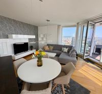 Wohnzimmer in einer 3-Zimmer-Wohnung mit einem runden Tisch und einem Boden in Holzoptik.