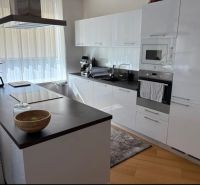 Küche in einer 3-Zimmer-Wohnung mit weißen Schränken und einem Boden in Holzoptik.