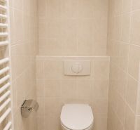 Badezimmer-WC in einer 2-Zimmer-Wohnung mit Fliesenboden und wandmontiertem Spülsystem.