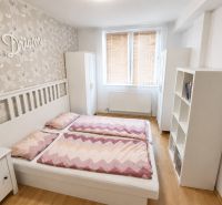 Helles Schlafzimmer mit Doppelbett, Blumen-Tapete und Holzboden.
