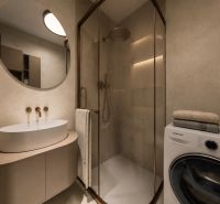 Badezimmer in einer 2-Zimmer-Wohnung mit Waschbecken, Waschmaschine und Duschkabine.