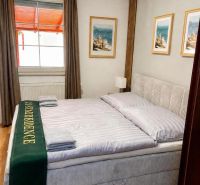 Helles Schlafzimmer in einem Einfamilienhaus mit großem Bett und Boden in Holzoptik.