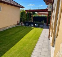 Der Garten des Einfamilienhauses in Darnózseli mit grünem Rasen und einem gepflasterten Weg.