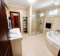 Badezimmer im Einfamilienhaus mit Doppelwaschbecken, Dusche und Badewanne.