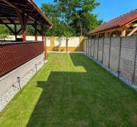 Der Garten eines Einfamilienhauses in Darnózseli mit Rasen, Pergola und von Bäumen umgeben.