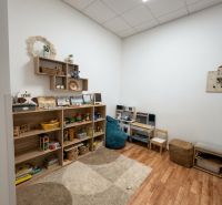 Kinderecke im Büro mit Regalen voller Spielzeug, Boden mit Holzdekor.