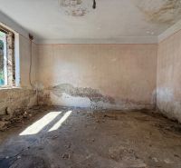 Verlassener Raum mit beschädigten Wänden und einem Fenster in einem Einfamilienhaus.
