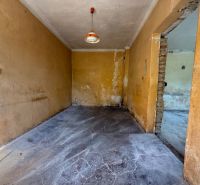Ein Zimmer in einem Einfamilienhaus mit Betonboden und orangefarbenen Wänden.